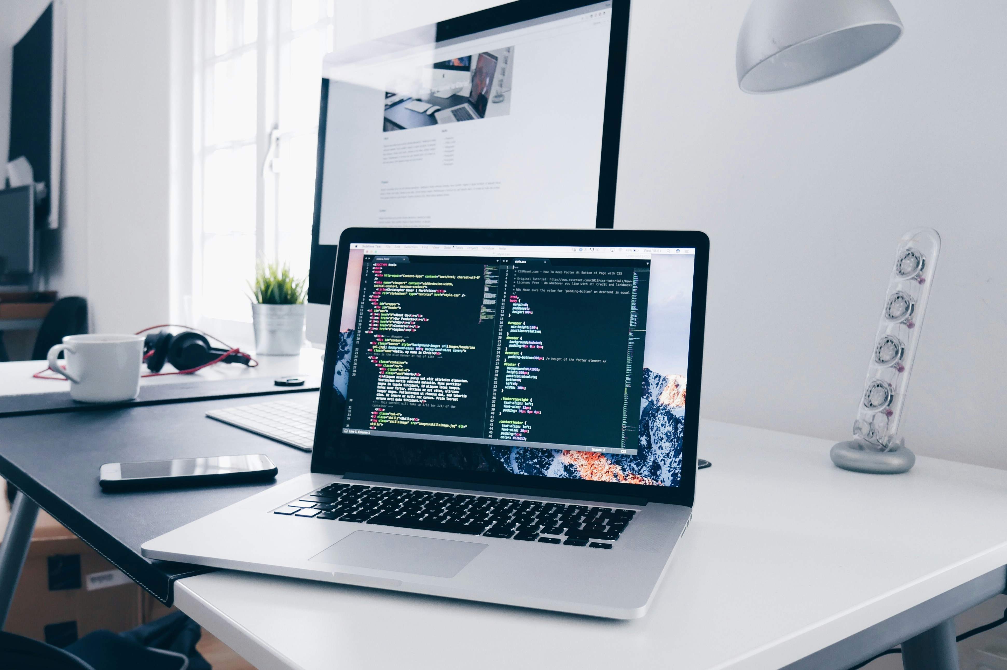 macbook-with-lines-of-code-on-its-screen-on-a-busy-desk