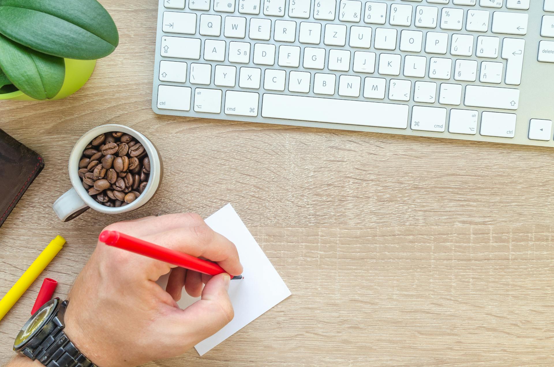 person-holding-red-pen-writing-on-white-paper