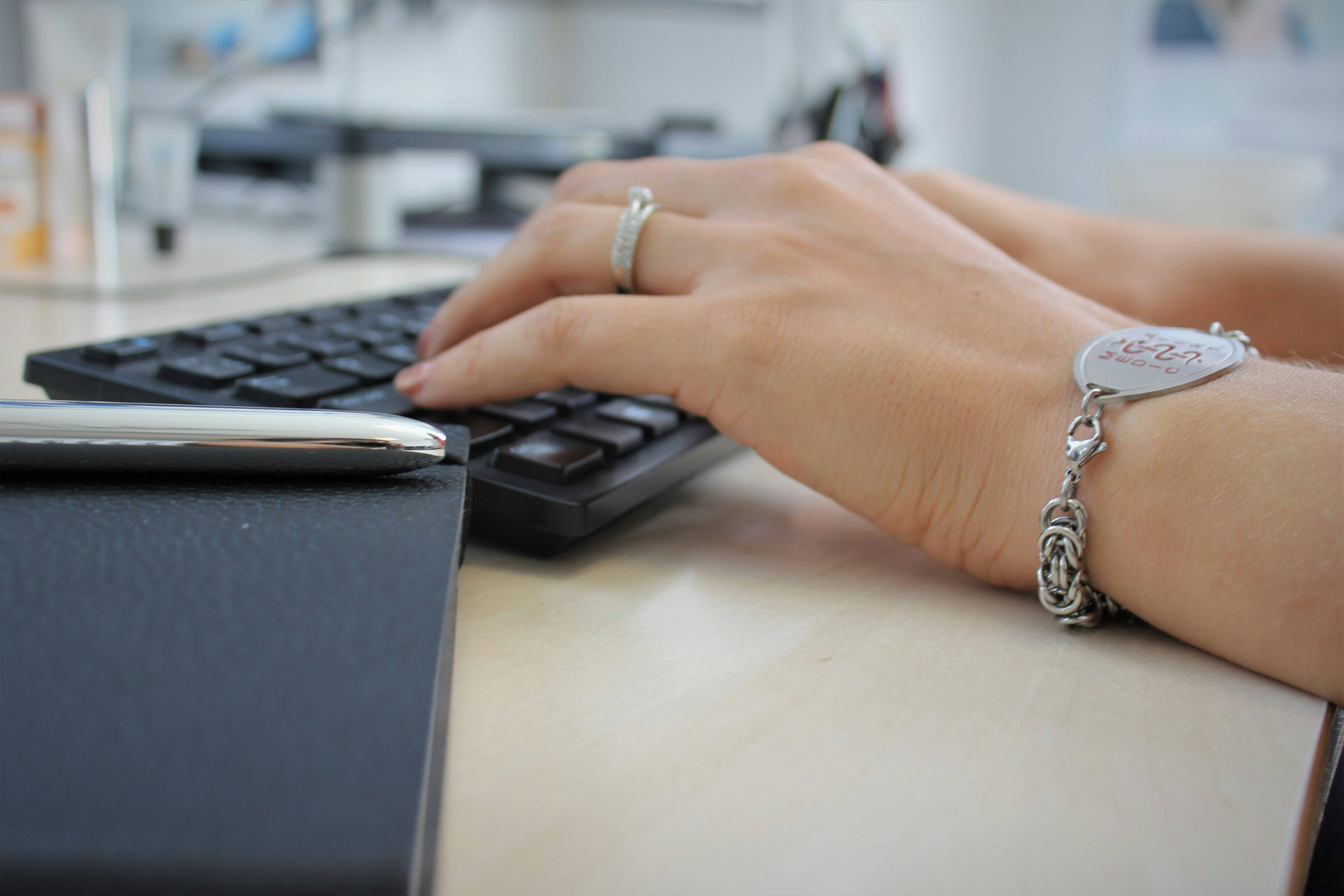 person-wearing-silver-ring-using-black-computer-keyboard