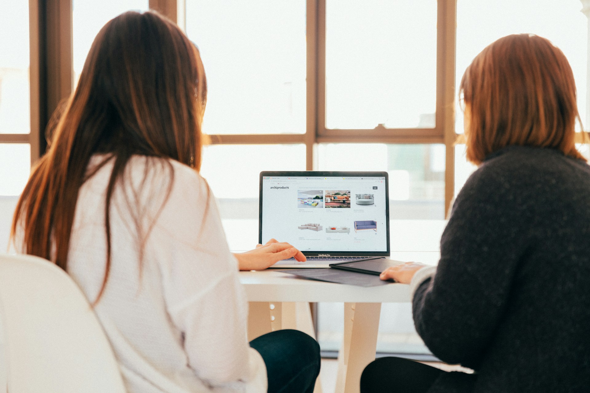 two-women-talking-while-looking-at-laptop-computer