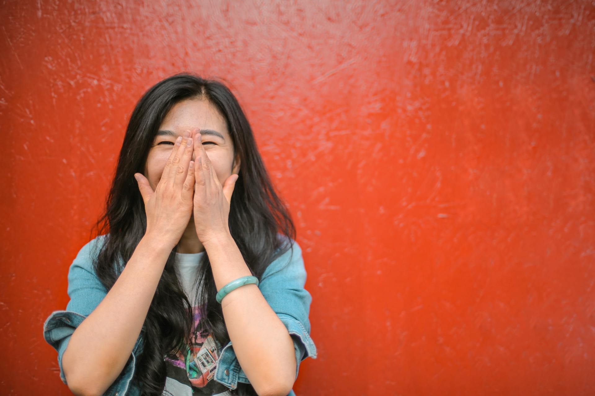 cheerful-ethnic-woman-against-vivid-red-painted-wall