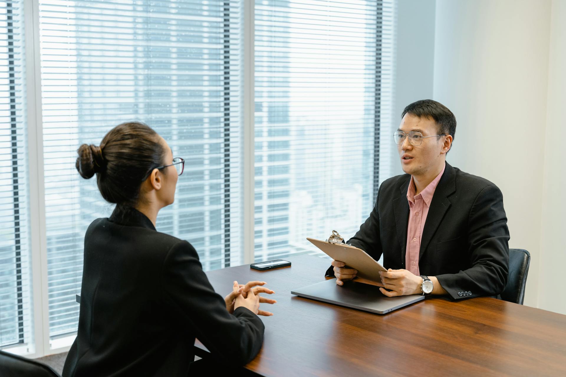 man-in-glasses-holding-a-folder-while-talking-to-a-woman-in-suit