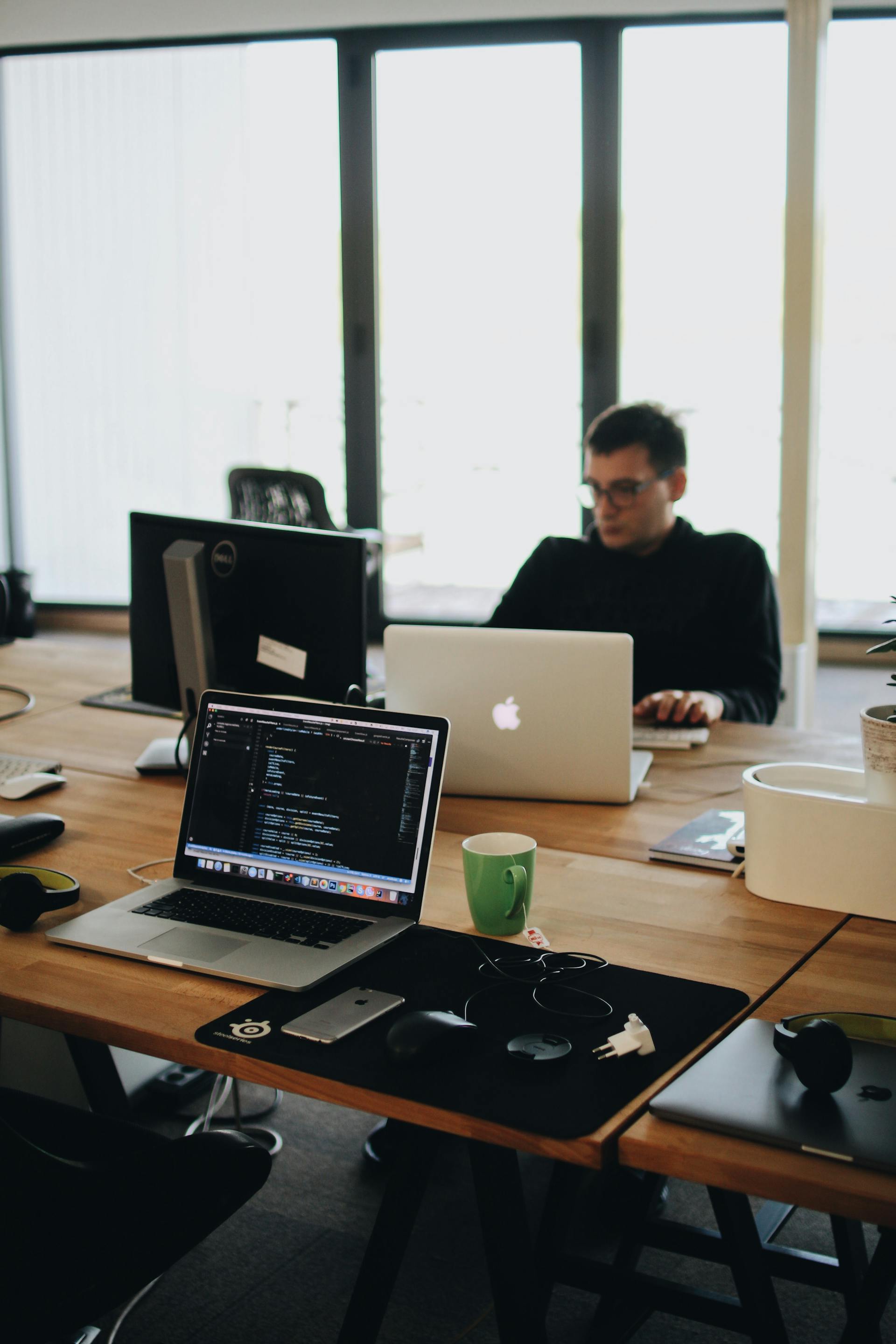 man-in-black-shirt-sits-behind-desk-with-computers