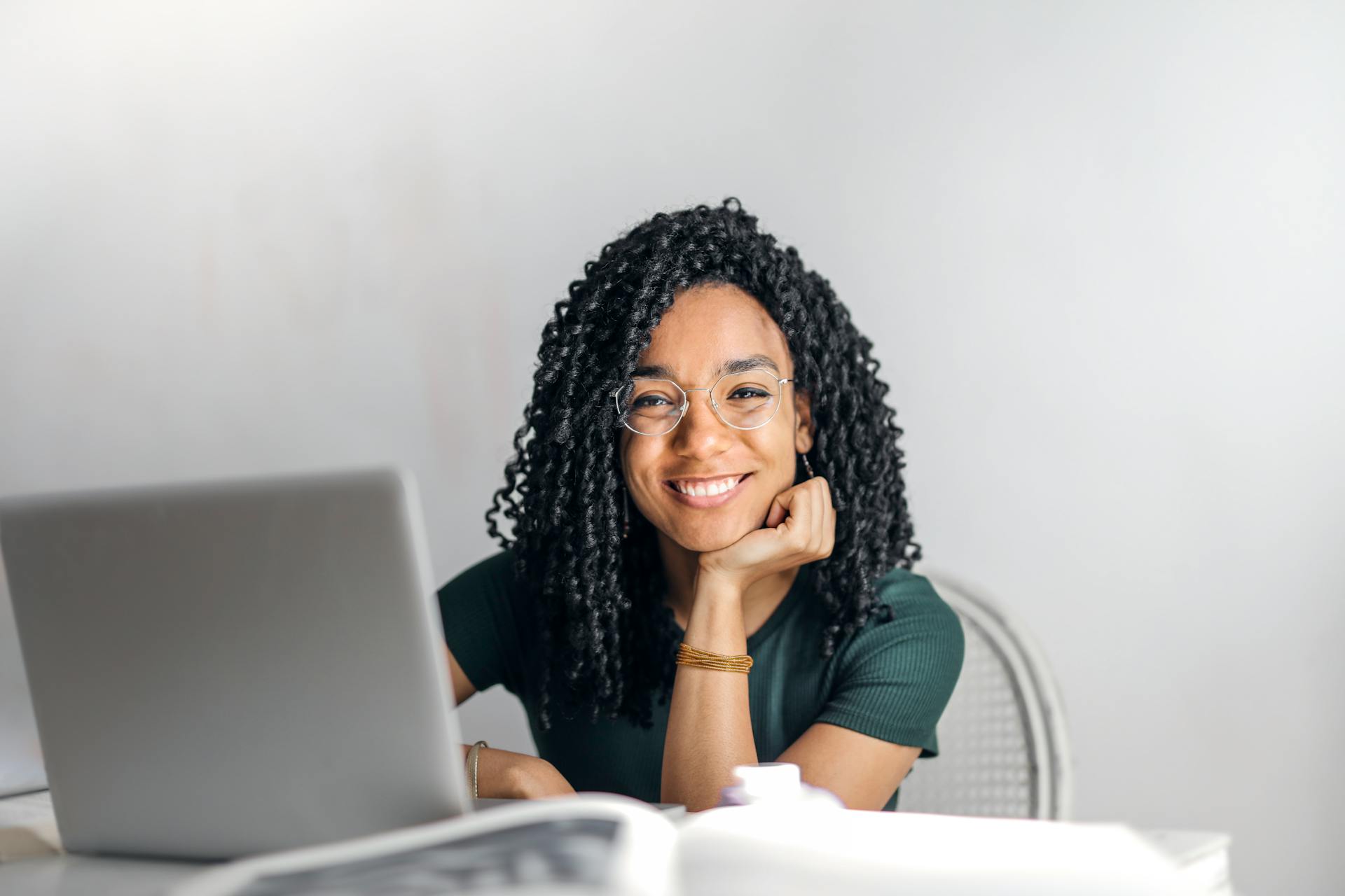 happy-ethnic-woman-sitting-at-table-with-laptop