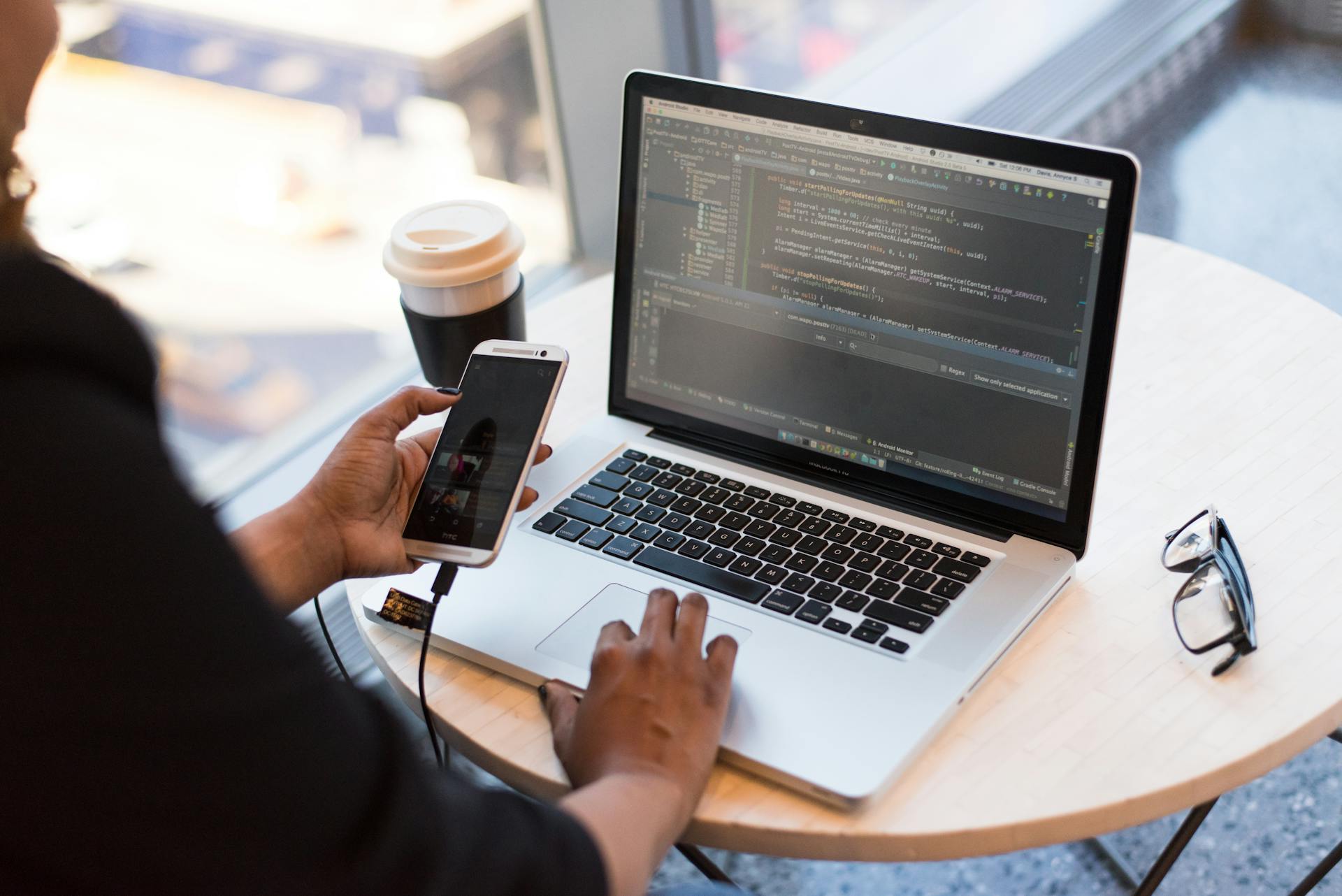 persoon-die-een-smartphone-vasthoudt-terwijl-hij-een-laptop-gebruikt