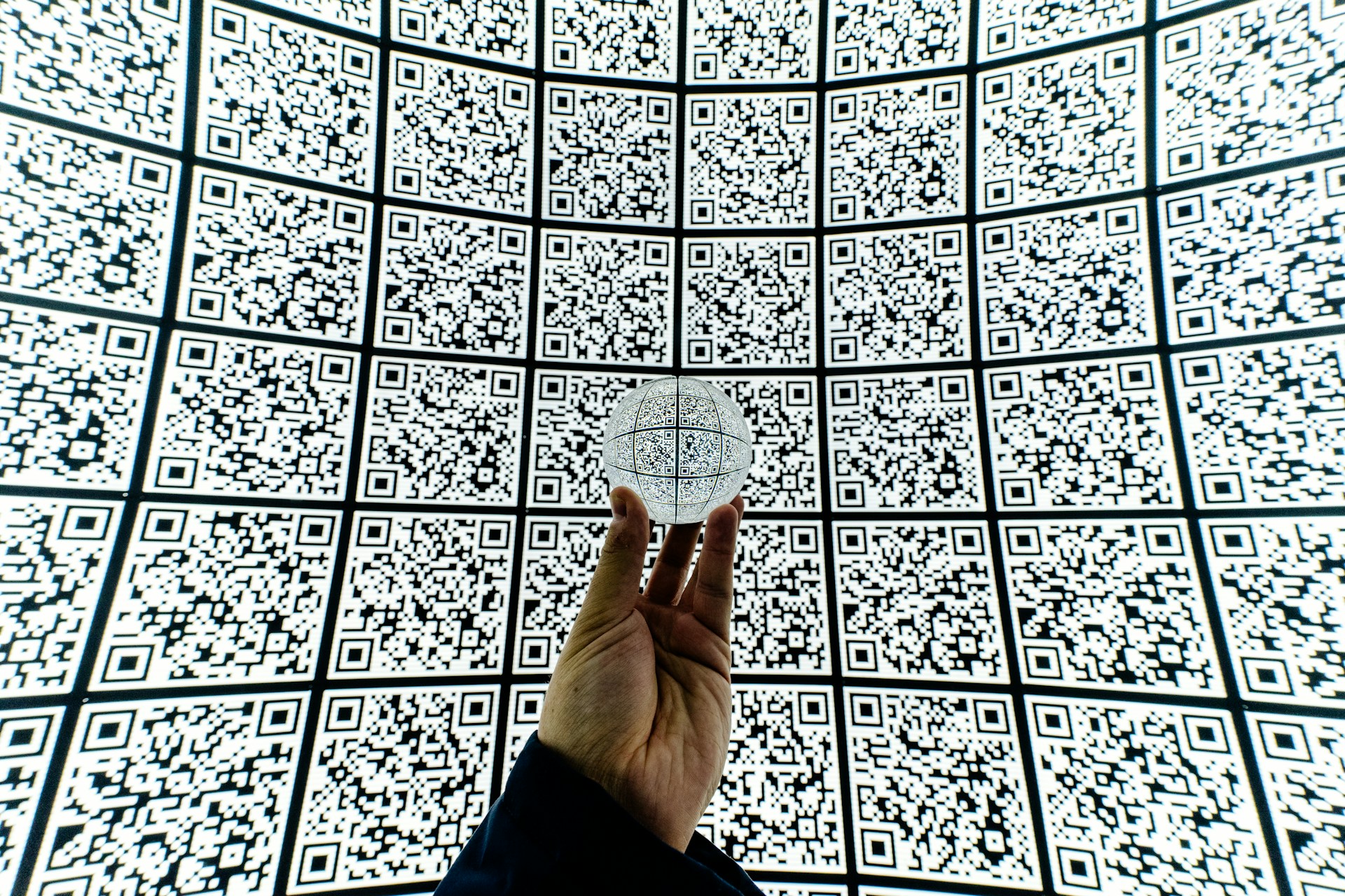 person-holding-clear-glass-ball-with-qr-code-background