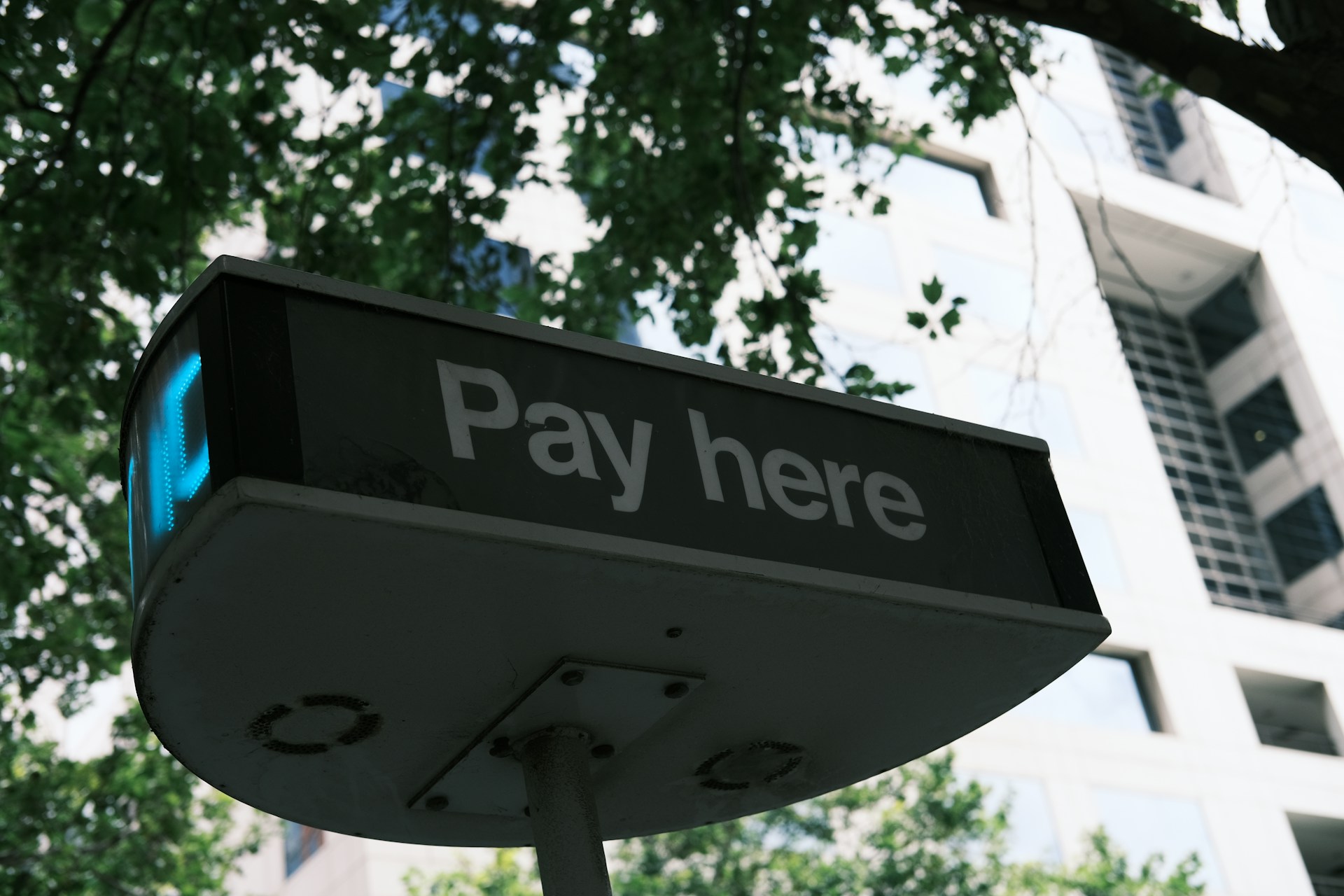 a-sign-that-says-pay-here-in-front-of-a-building