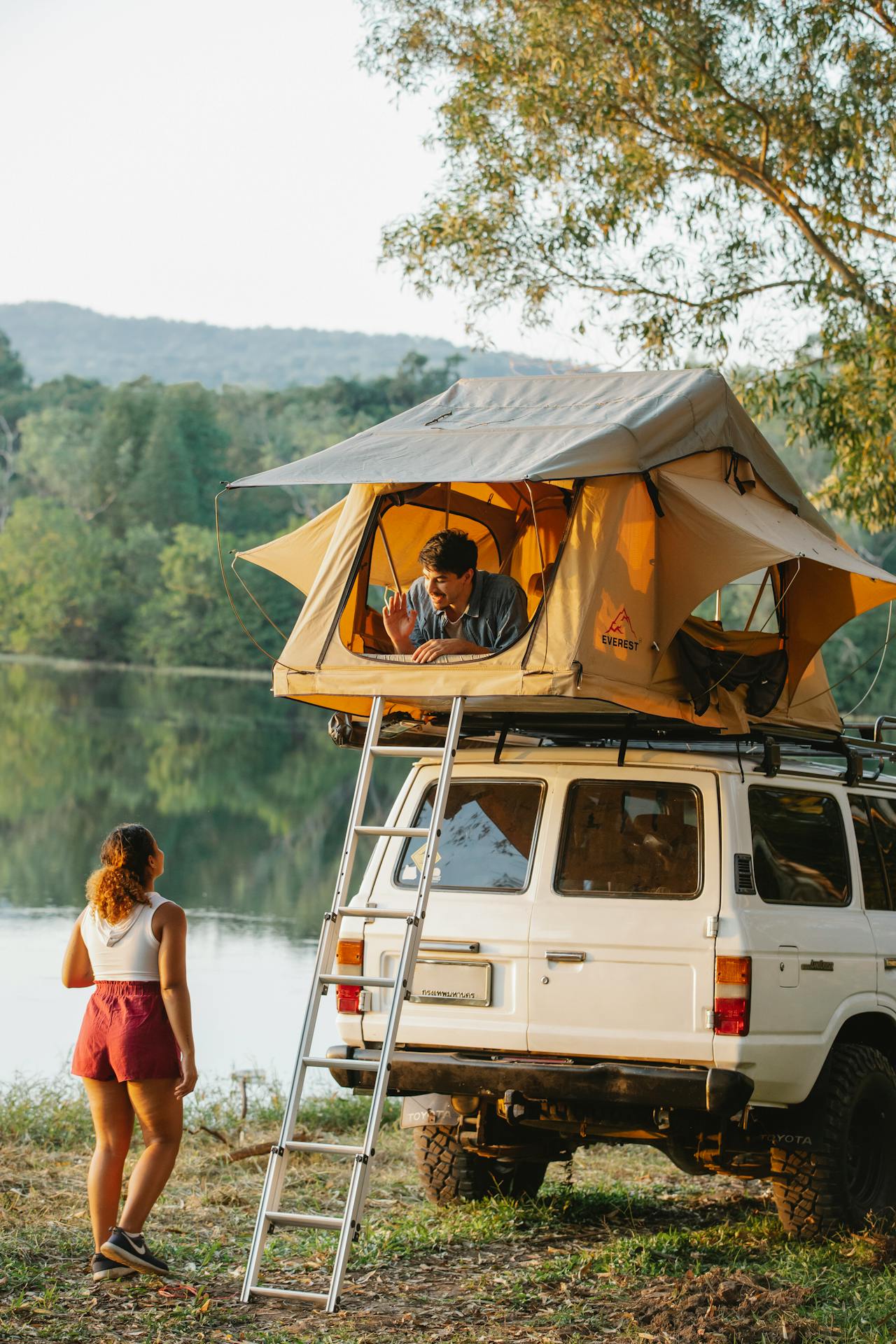 anonymous-young-couple-chatting-during-camping-on-lake-shore