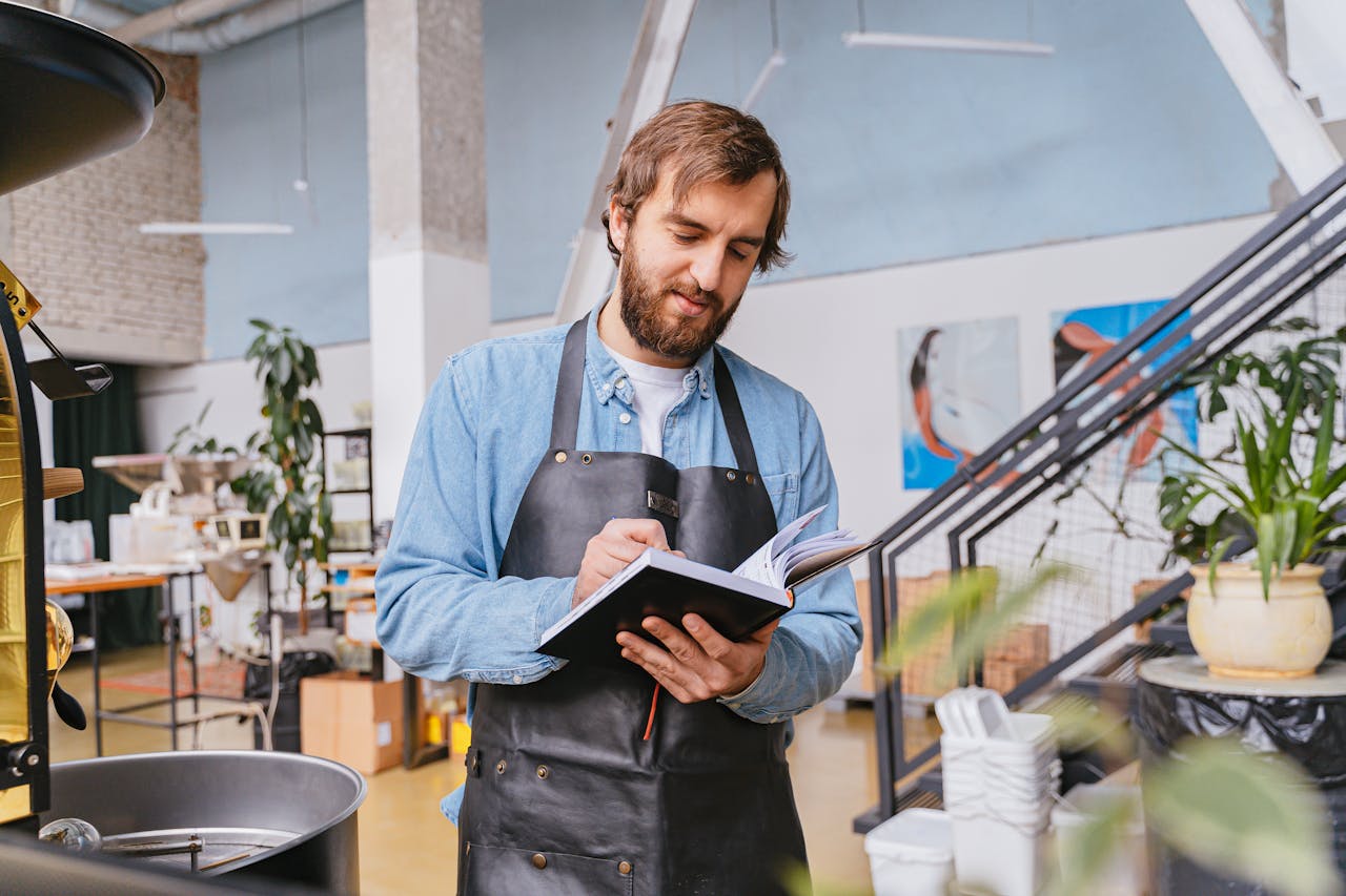 man-wearing-black-apron-writing-on-a-notebook