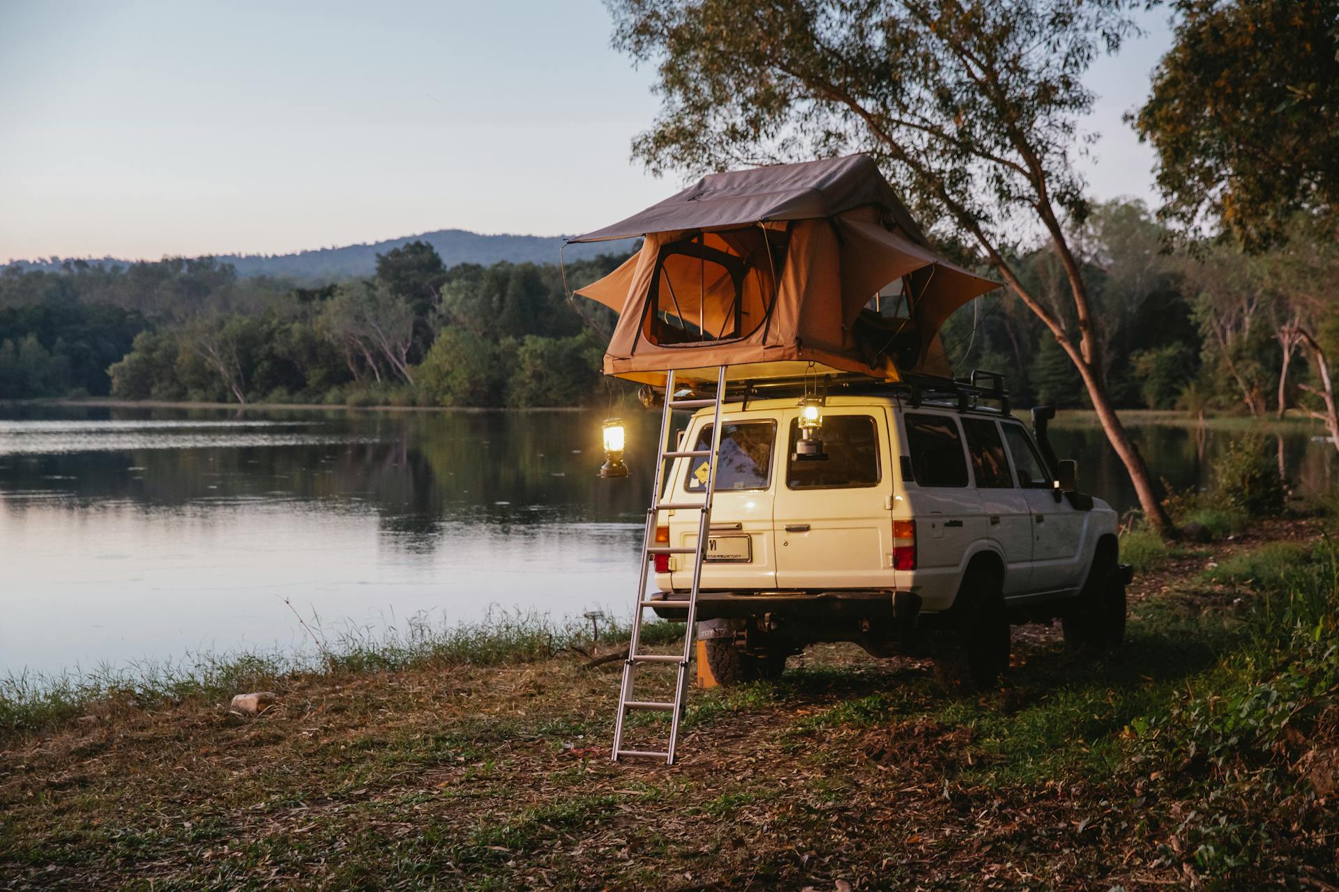 suv-car-with-camping-tent-parked-on-lake-coast-in-woods-during-road-trip